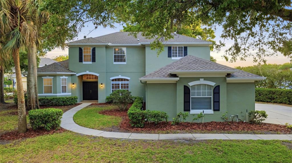A two-story green stucco house with a shingled roof and a curved concrete walkway — 1545 CHERRY RIDGE DRIVE, LAKE MARY, FL