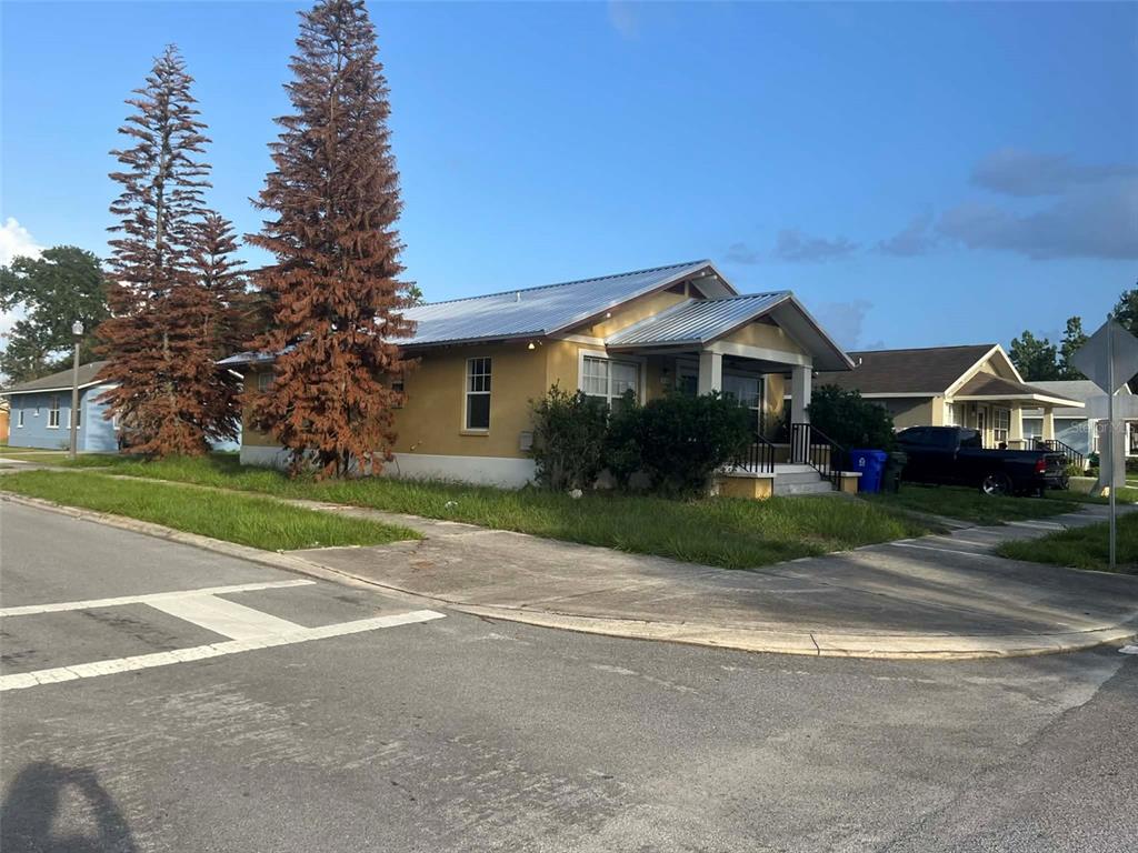 A yellow single-story house with a metal roof sits on a corner lot — 1155 N FLORENCE AVENUE, LAKELAND, FL