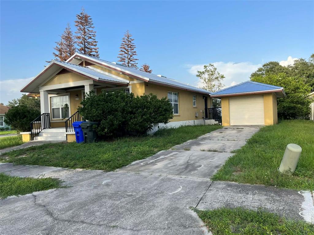 A yellow single-story house with a metal roof, front porch, and detached garage — 1155 N FLORENCE AVENUE, LAKELAND, FL