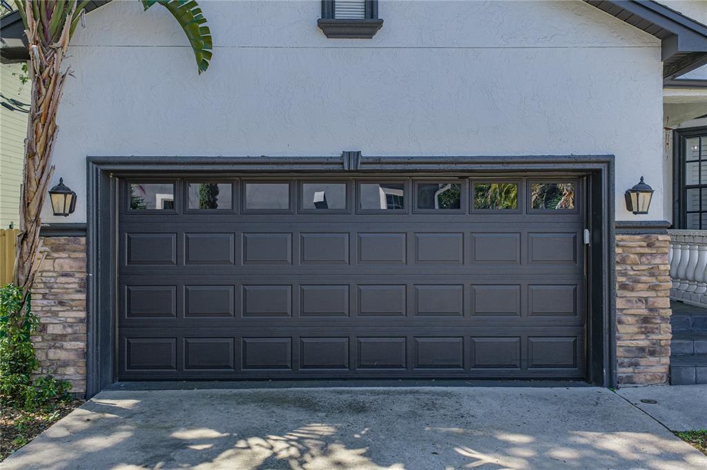 A dark gray garage door with rectangular panels and a row of windows — 6117 S RUSSELL STREET, TAMPA, FL