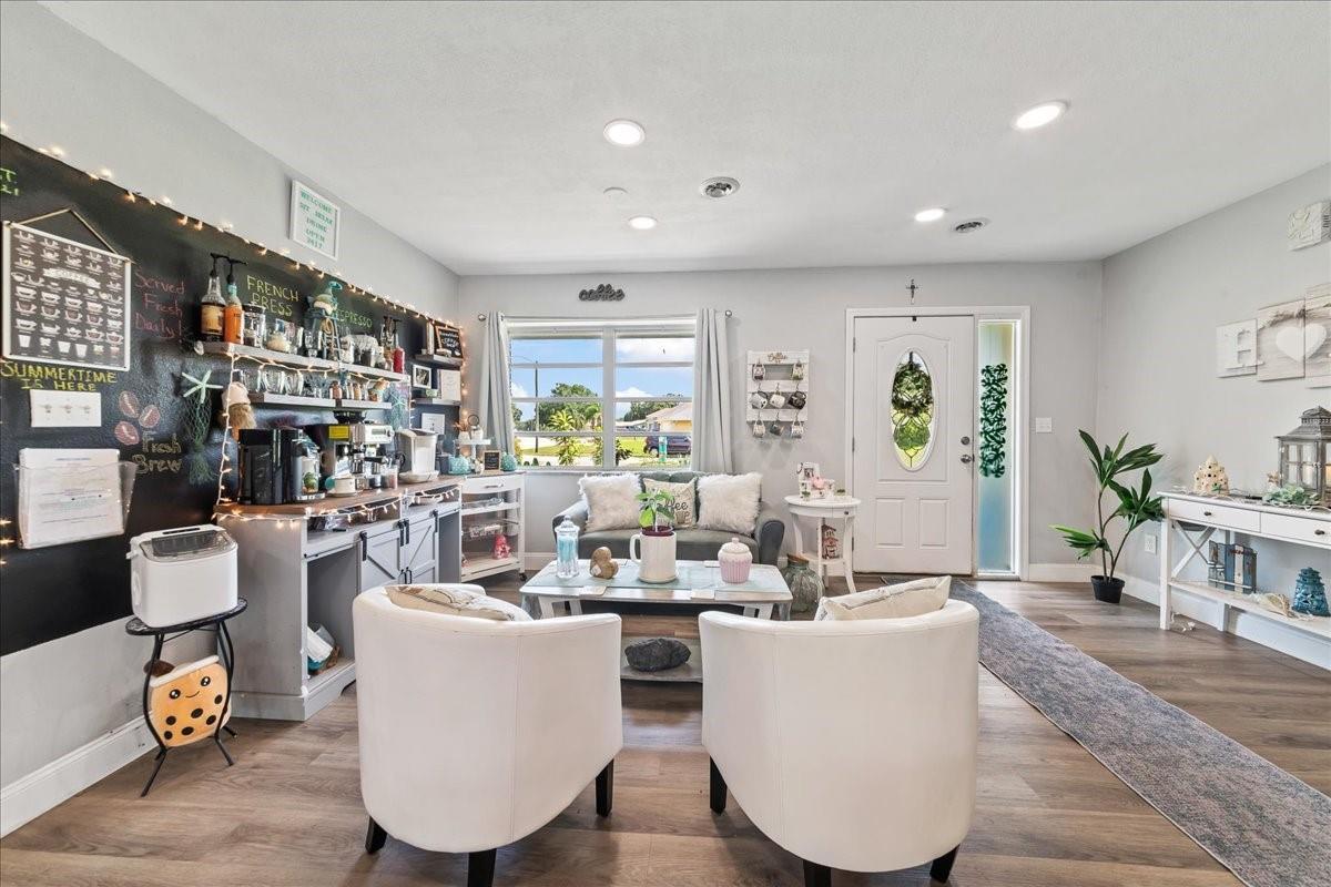 A living room features a coffee station, white armchairs, a sofa, and a front door — 573 Wimbrow Drive, Sebastian FL 32958, SEBASTIAN, FL