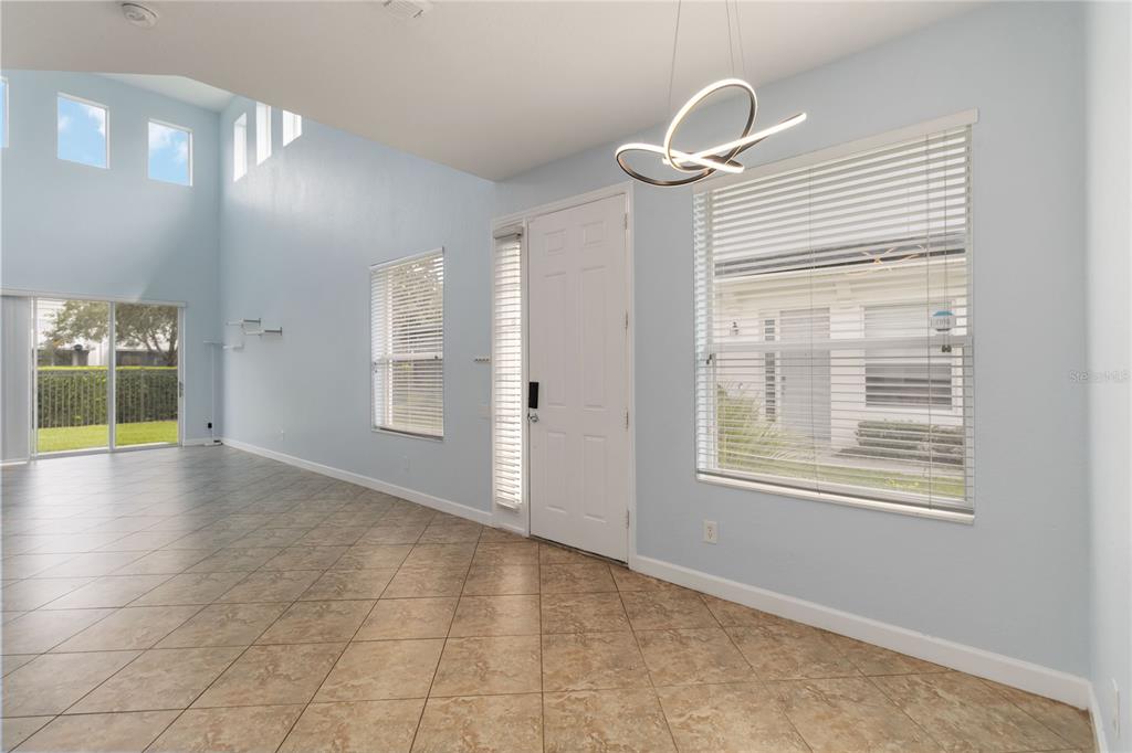 An entryway with light blue walls, tile flooring, a modern chandelier, and high ceilings — 1706 SHALLCROSS AVENUE, ORLANDO, FL