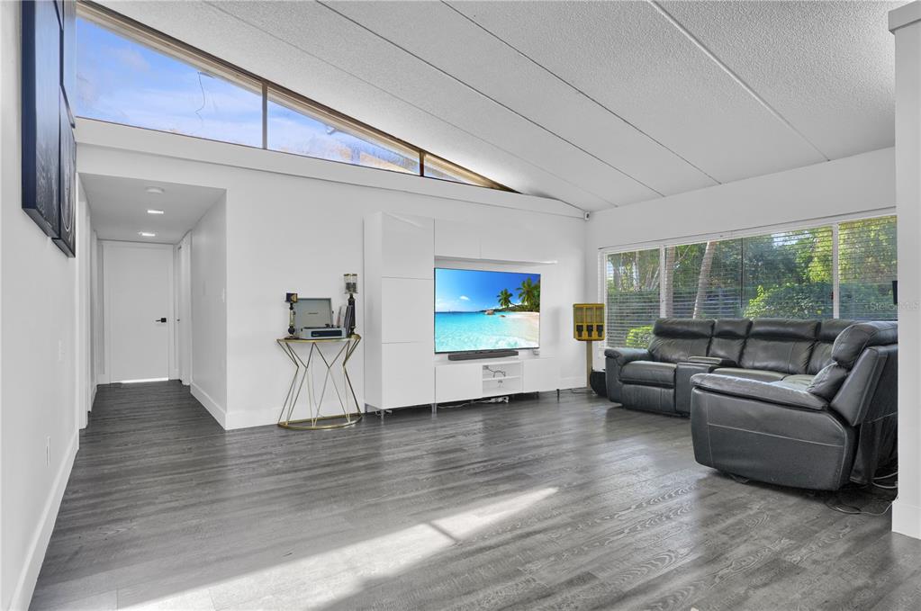 A living room features gray wood-look flooring, a white entertainment unit, and a black sofa — 19755 SW 241ST TERRACE, HOMESTEAD, FL