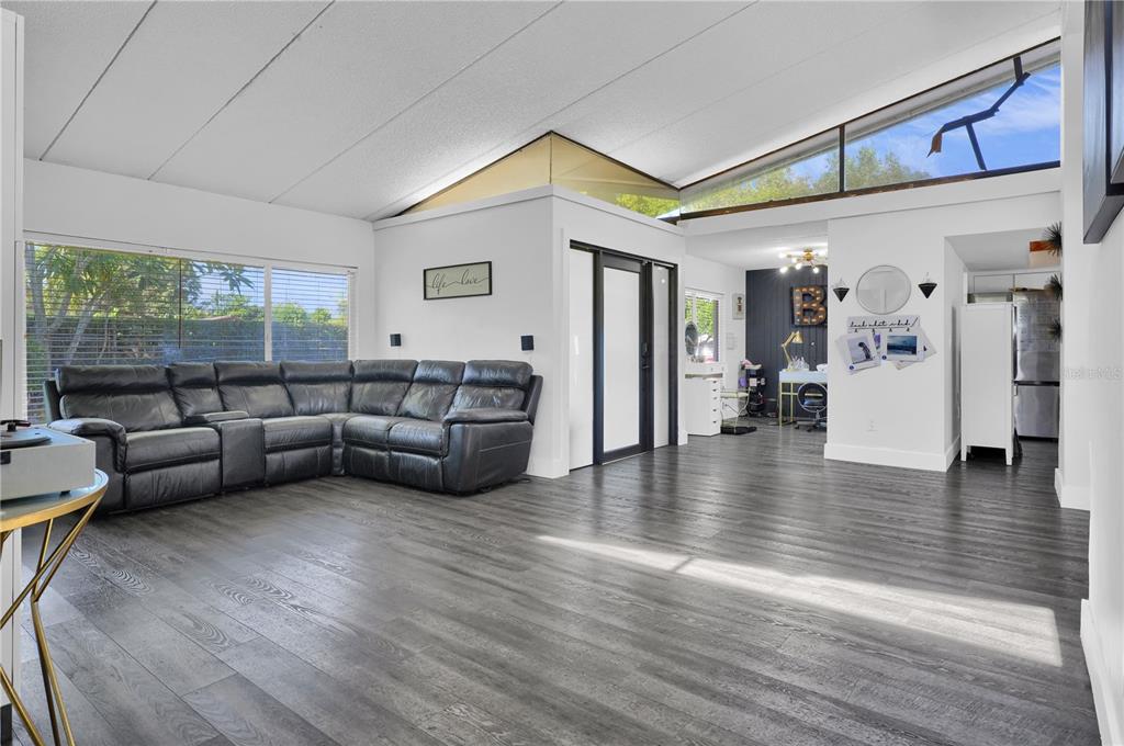 A living room features gray wood-look flooring, a large black sectional sofa, and vaulted ceilings — 19755 SW 241ST TERRACE, HOMESTEAD, FL