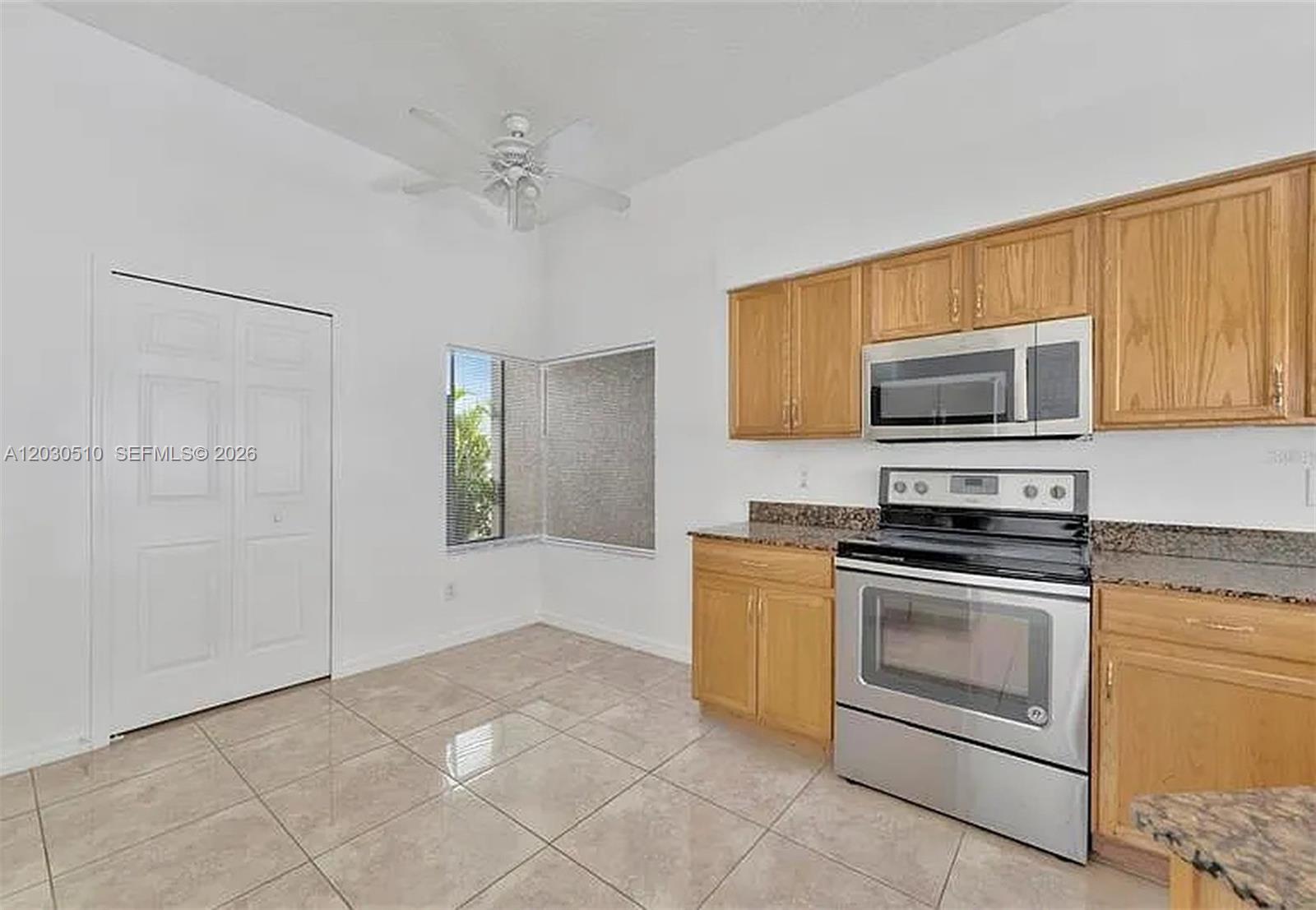 A kitchen features light wood cabinets, stainless steel appliances, granite countertops, and tiled flooring — 11007 Whitecap Dr, Riverview FL 33579, RIVERVIEW, FL