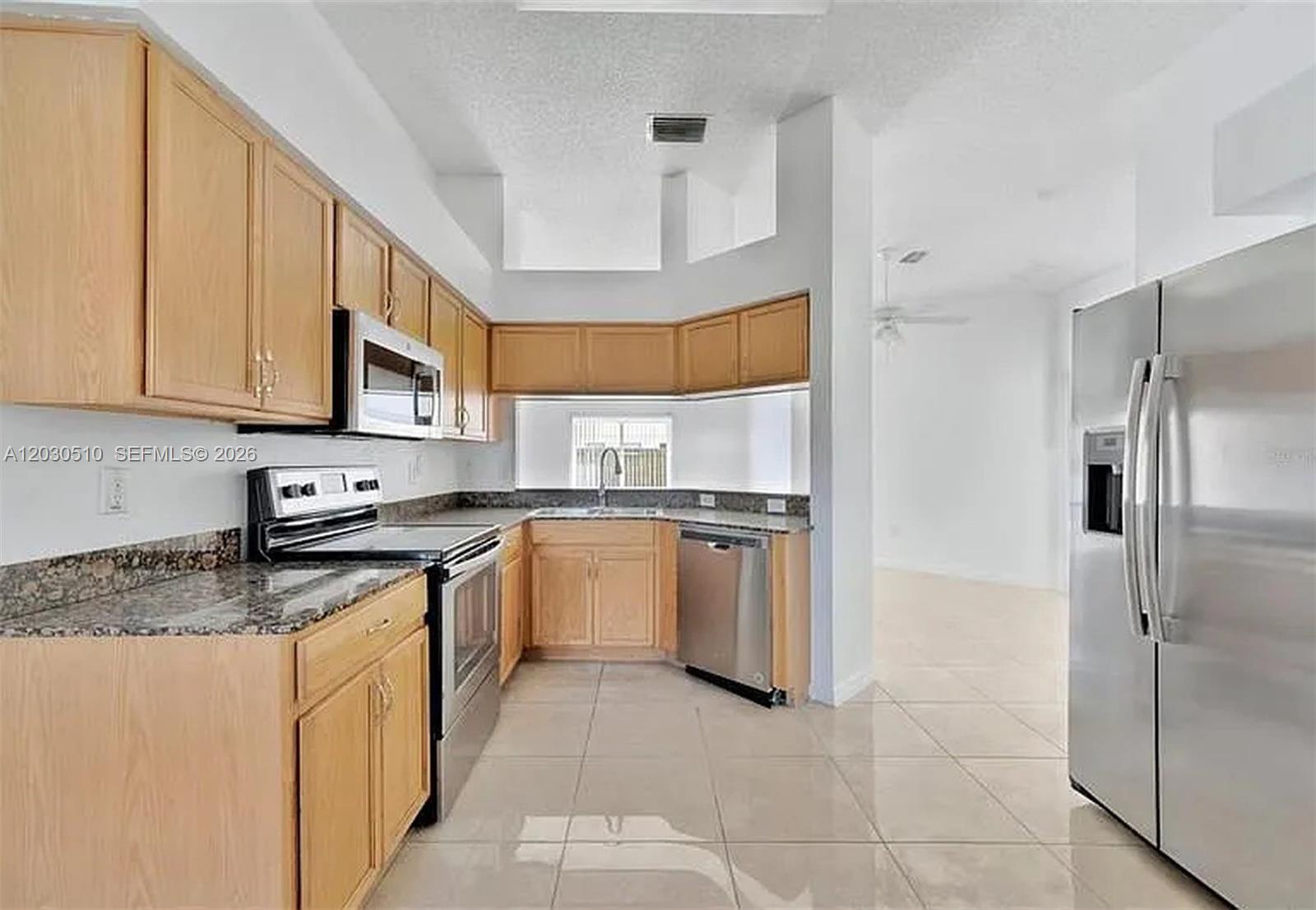 A kitchen features light wood cabinets, granite countertops, stainless steel appliances, and tile flooring — 11007 Whitecap Dr, Riverview FL 33579, RIVERVIEW, FL