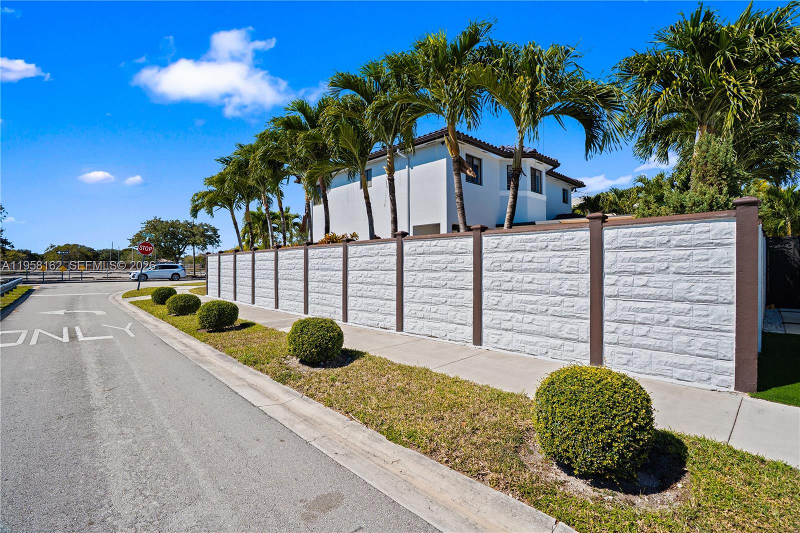 A white house stands behind a tall, textured wall with brown posts and palm trees — 3281 SW 145th Ave, Miami FL 33175, MIAMI, FL