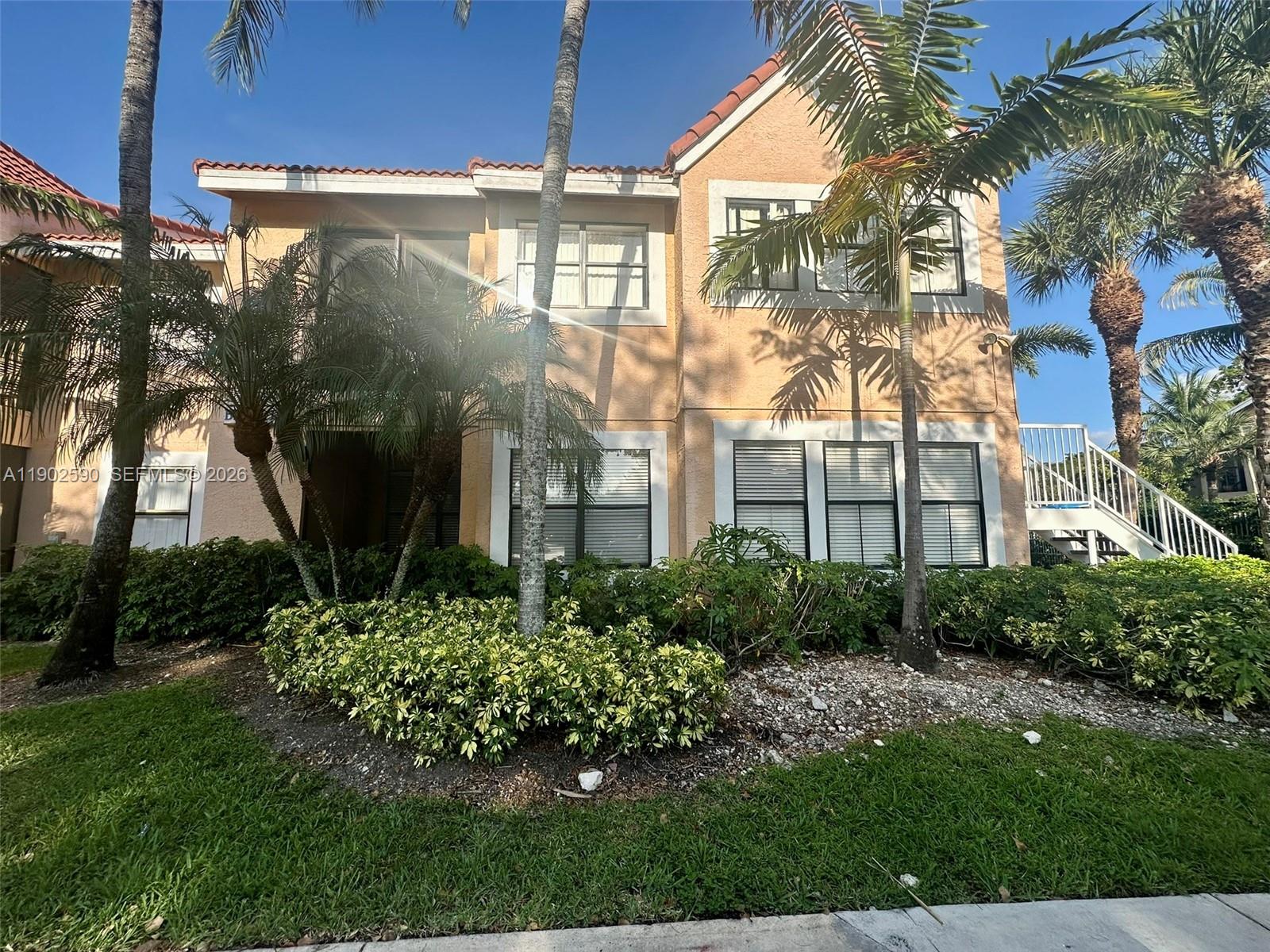 A two-story tan stucco building features a tiled roof, palm trees, and landscaping — 10581 SW 155th Ct # 1214, Miami FL 33196, MIAMI, FL