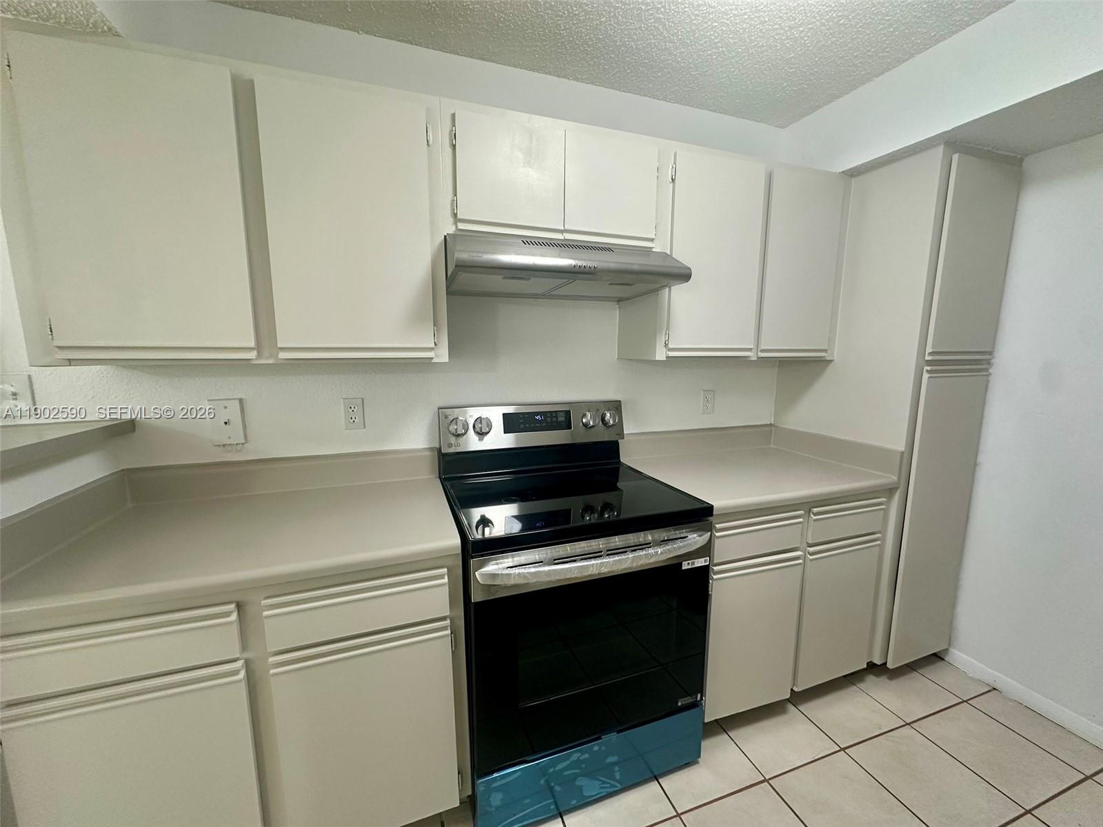 A kitchen features white cabinets, a black electric stove, and light-colored countertops — 10581 SW 155th Ct # 1214, Miami FL 33196, MIAMI, FL