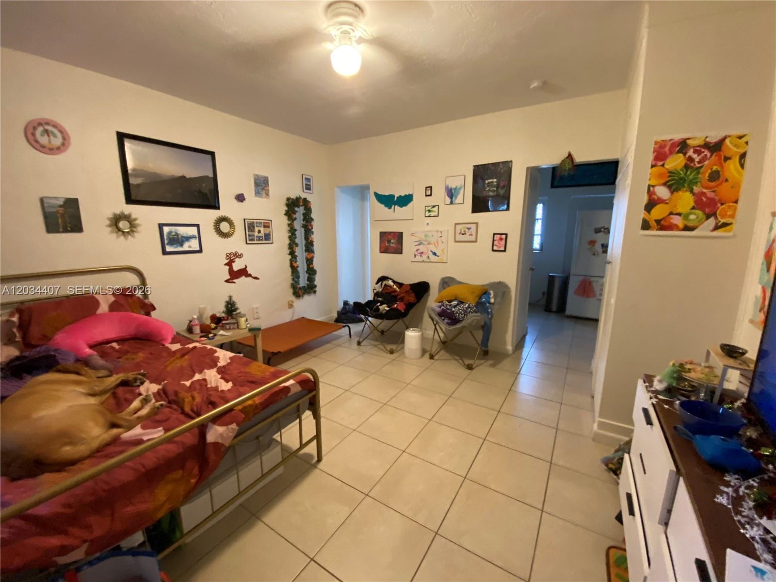A bedroom features tiled floors, a metal-framed bed with a dog, and various wall art — 730 SW 10th St # 4, Miami FL 33130, MIAMI, FL