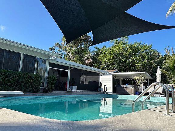 A swimming pool sits in front of a house with a large black shade sail — 186 12th Street SE, Vero Beach FL 32962, VERO BEACH, FL