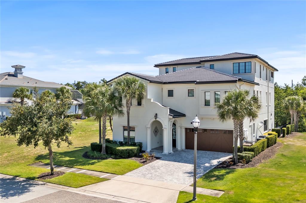 A three-story stucco house with a tile roof, arched entryway, and a paved driveway — 550 MUIRFIELD LOOP, KISSIMMEE, FL