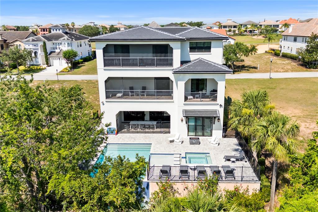An aerial view of a three-story white house with a pool, patio, and balconies — 550 MUIRFIELD LOOP, KISSIMMEE, FL
