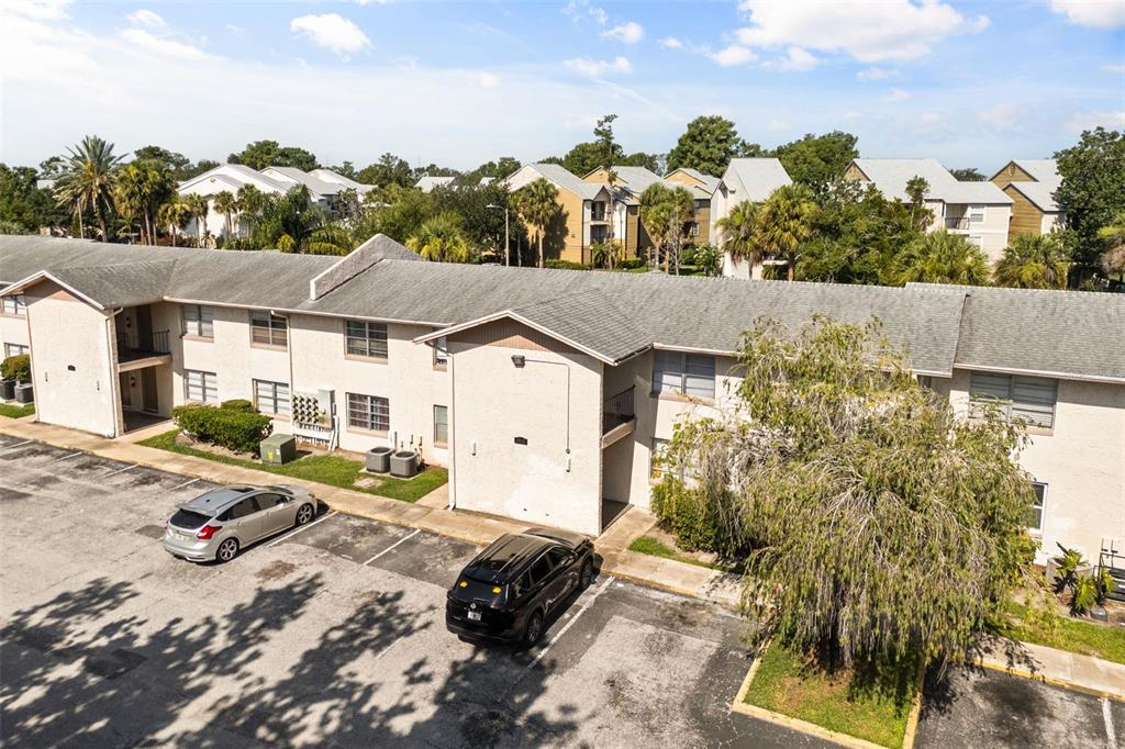 An aerial view shows a two-story apartment building with a parking lot and trees — 1910 HONOUR ROAD UNIT 4, ORLANDO, FL