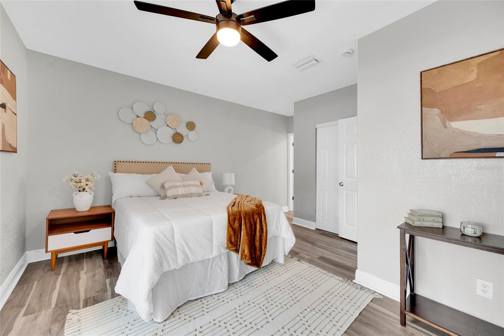 A bedroom features a bed with white bedding, a ceiling fan, and wood-look flooring — 429 E OAKWOOD STREET, TARPON SPRINGS, FL