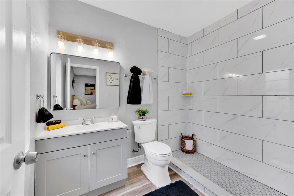 A bathroom features a gray vanity, a white toilet, and a walk-in shower with white tiles — 429 E OAKWOOD STREET, TARPON SPRINGS, FL
