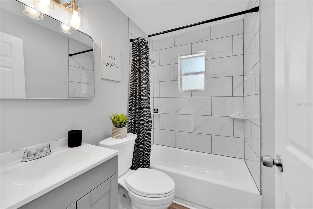 A bathroom features a gray vanity, a white toilet, and a tiled shower-tub combination — 429 E OAKWOOD STREET, TARPON SPRINGS, FL