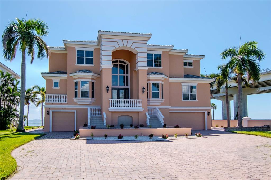 A large, two-story peach-colored house with a paved driveway and palm trees — 7680 PARADISE POINTE CIRCLE S, ST PETERSBURG, FL