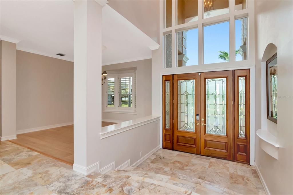 An entryway with tile flooring, a double wood front door, and a sunken living area — 7680 PARADISE POINTE CIRCLE S, ST PETERSBURG, FL