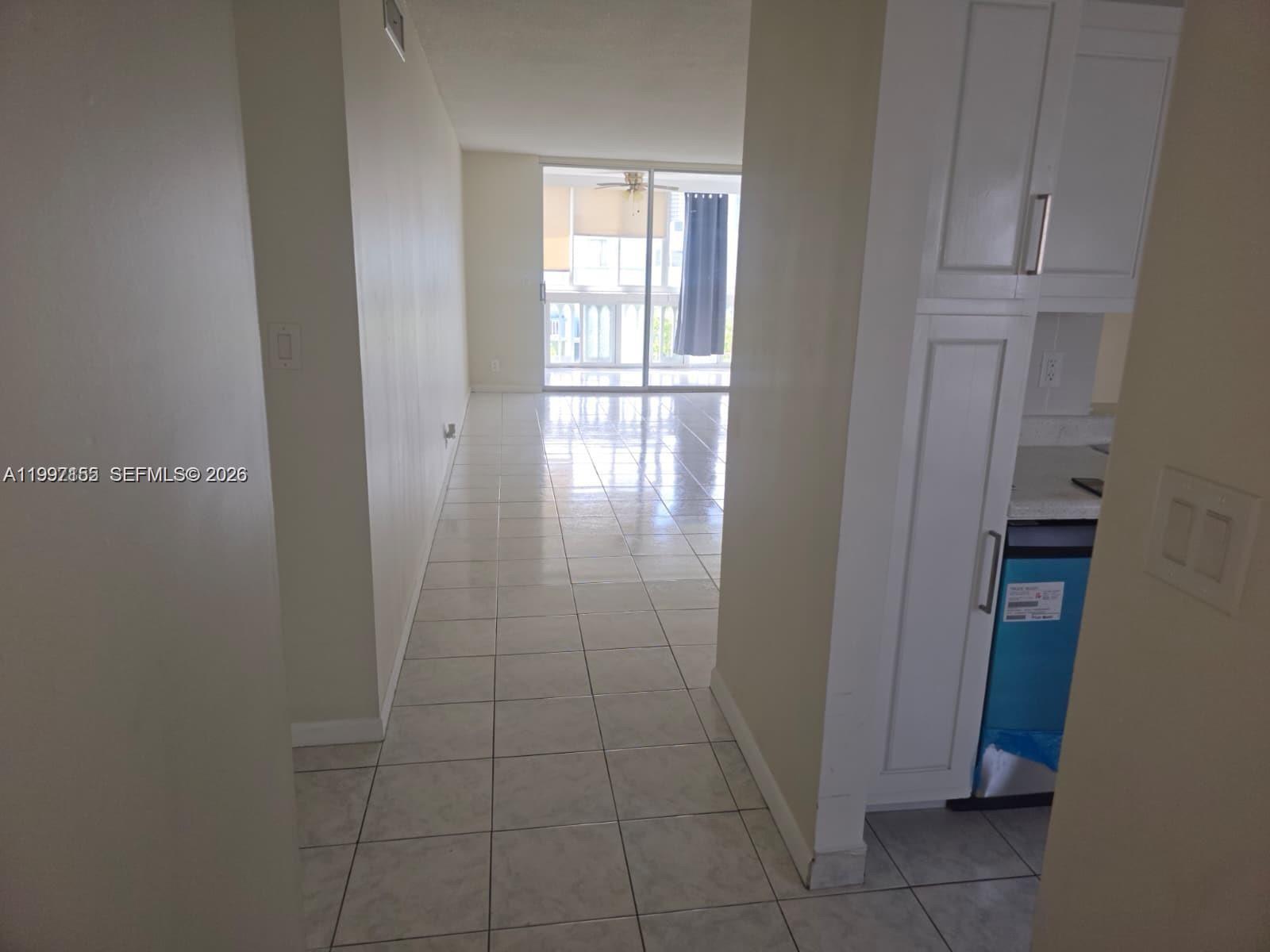 A tiled hallway leads to a living area with a sliding glass door to a balcony — 320 NE 12th Ave # 703, Hallandale Beach FL 33009, HALLANDALE BEACH, FL