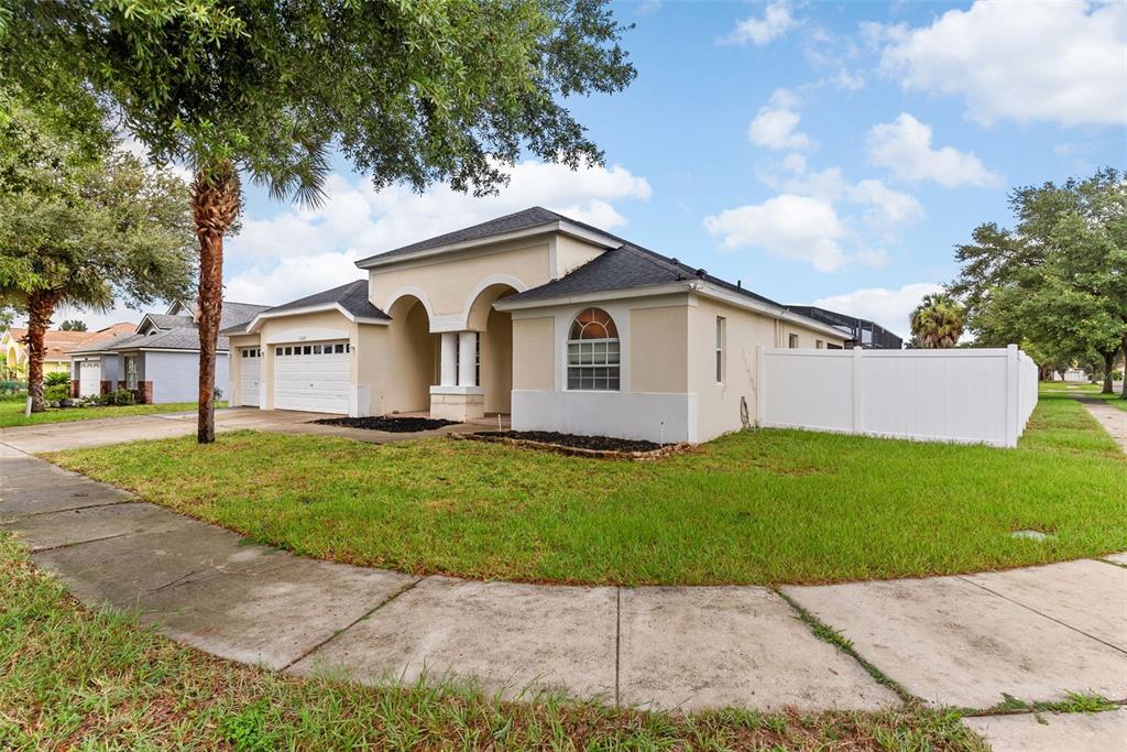 A single-story house with a beige stucco exterior, a two-car garage, and a white fence — 16222 EGRET HILL STREET, CLERMONT, FL