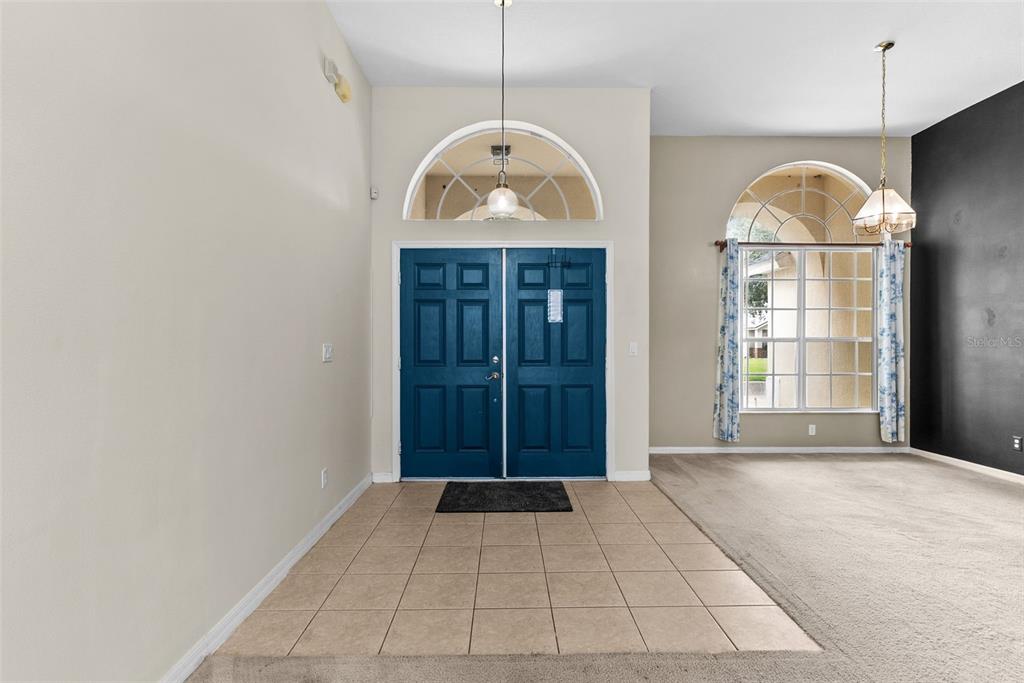 An entryway with a blue double door, tiled floor, and a large arched window — 16222 EGRET HILL STREET, CLERMONT, FL