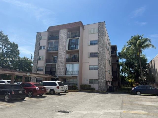 A multi-story apartment building features balconies and a parking lot with several parked cars — 3640 NW 9th St # 201, Miami FL 33125, MIAMI, FL