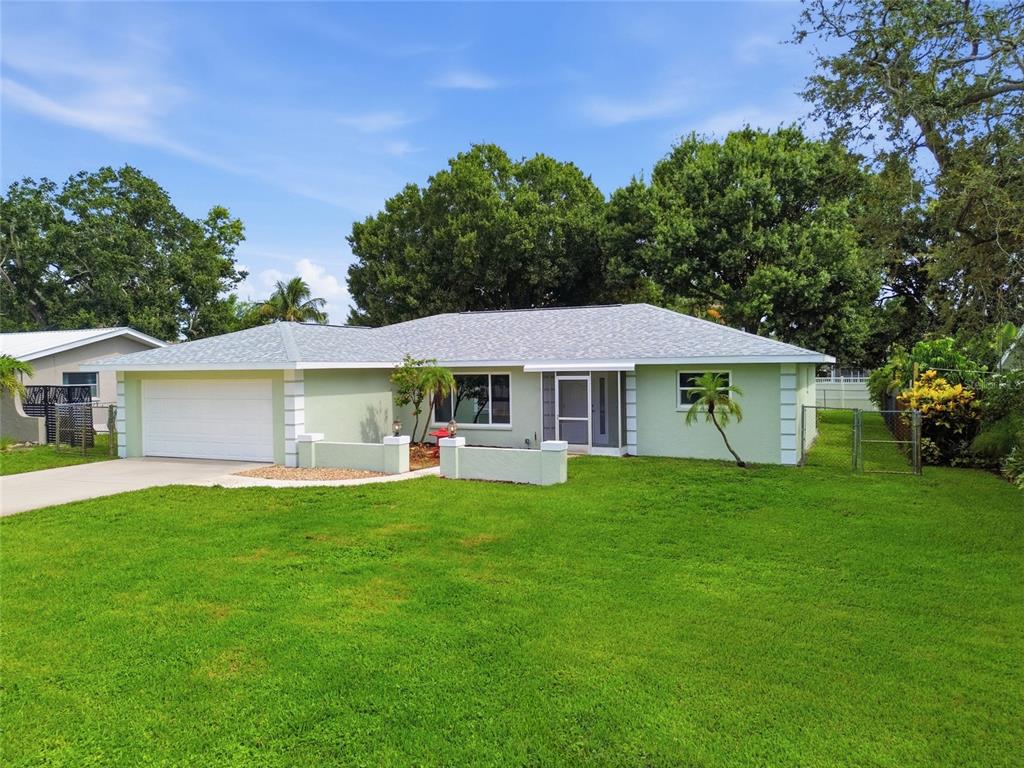 A light green single-story house with a white garage door and a grassy front yard — 5608 4TH AVENUE NW, BRADENTON, FL