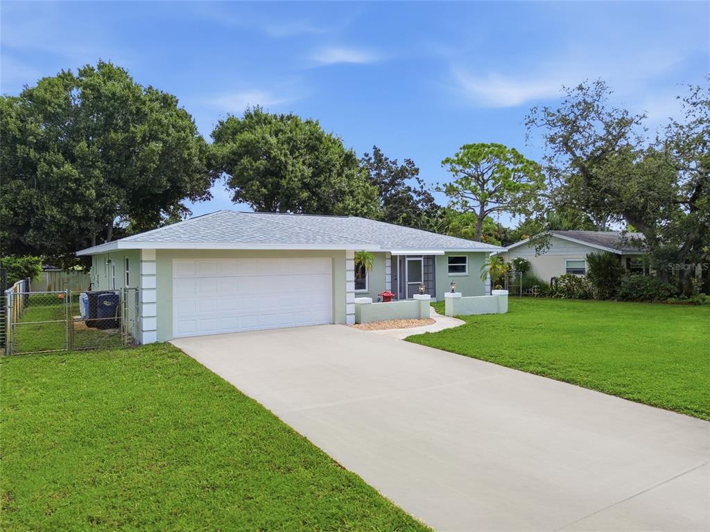 A single-story house with a light green exterior, a white garage door, and a concrete driveway — 5608 4TH AVENUE NW, BRADENTON, FL