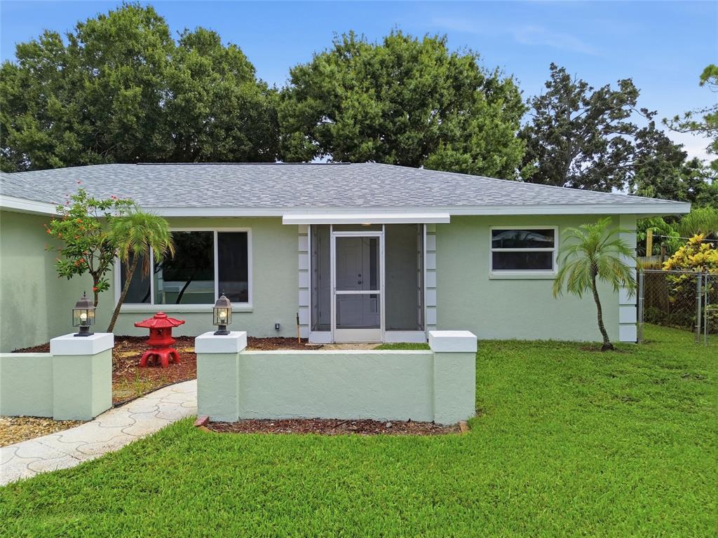 A light green single-story house features a screened front entryway and a low masonry wall — 5608 4TH AVENUE NW, BRADENTON, FL