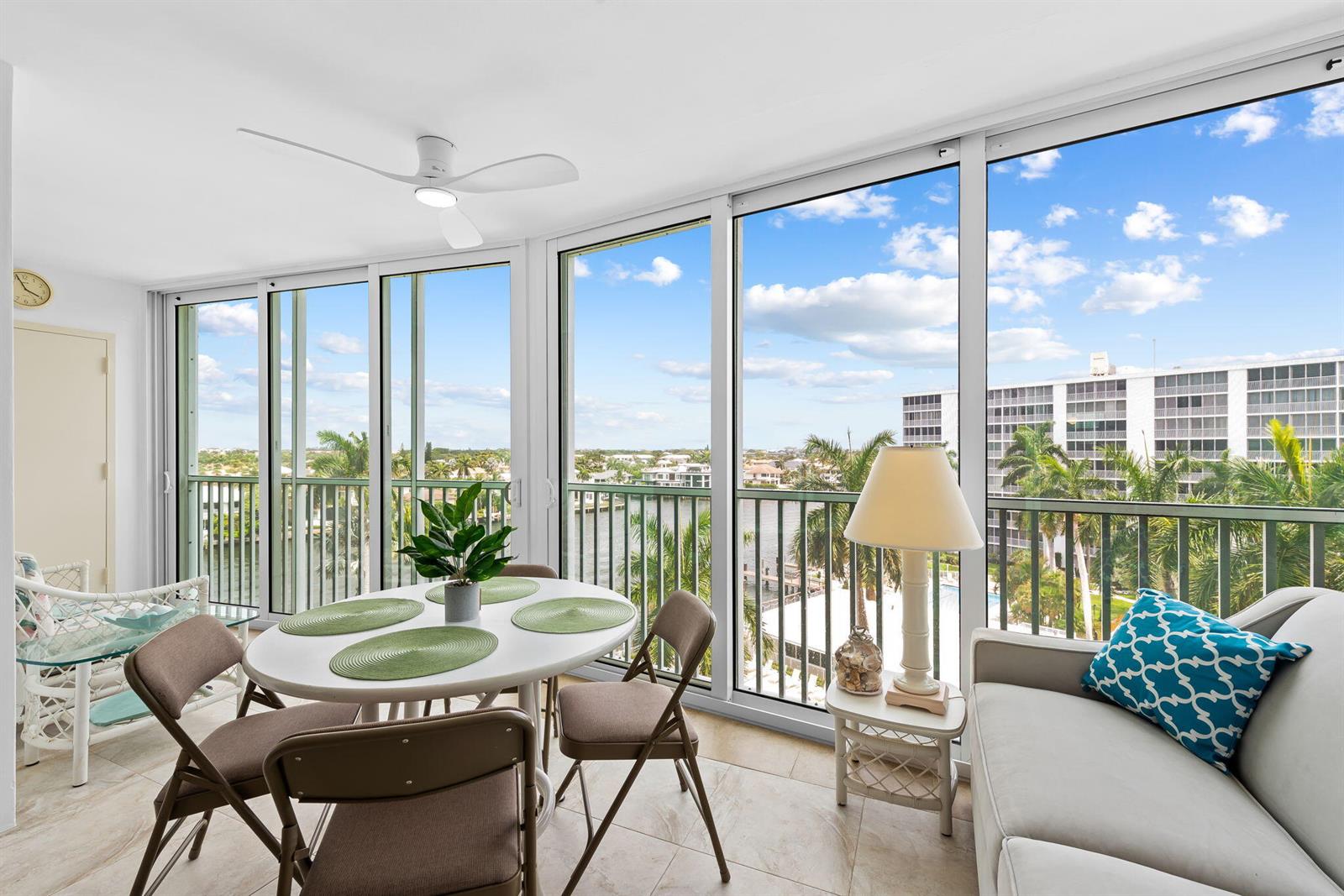 A sunroom features a dining set, a sofa, and floor-to-ceiling windows overlooking a waterway — 3300 S Ocean Boulevard # c, Highland Beach FL 33487, HIGHLAND BEACH, FL