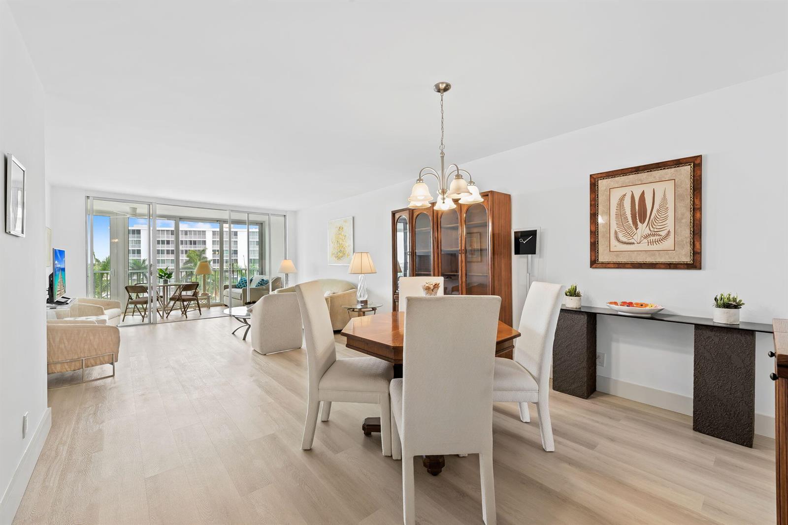A bright dining and living area features light wood flooring, a glass-topped table, and balcony access — 3300 S Ocean Boulevard # c, Highland Beach FL 33487, HIGHLAND BEACH, FL