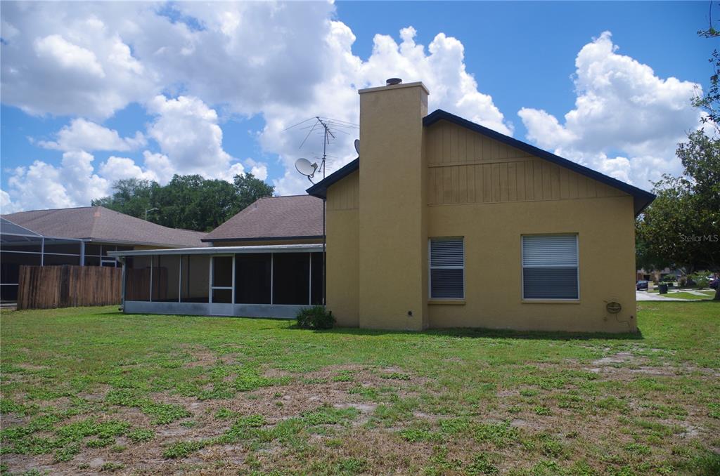 The exterior of a tan house features a chimney, a screened-in porch, and a grassy yard — 4207 ELBA PLACE, VALRICO, FL