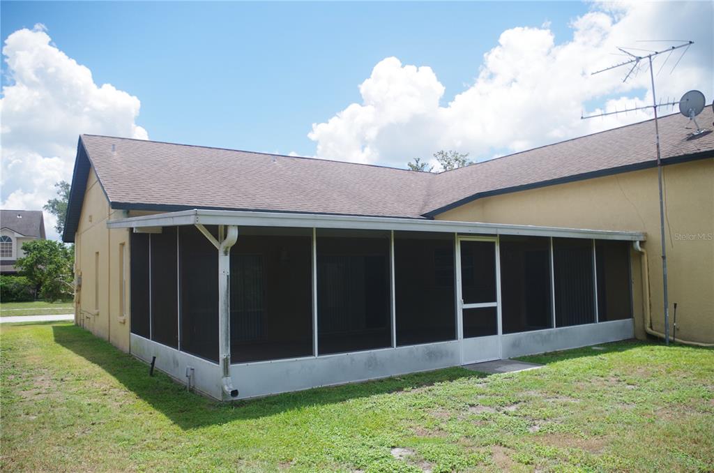 A tan house features a large screened-in porch with a white frame and metal roof — 4207 ELBA PLACE, VALRICO, FL