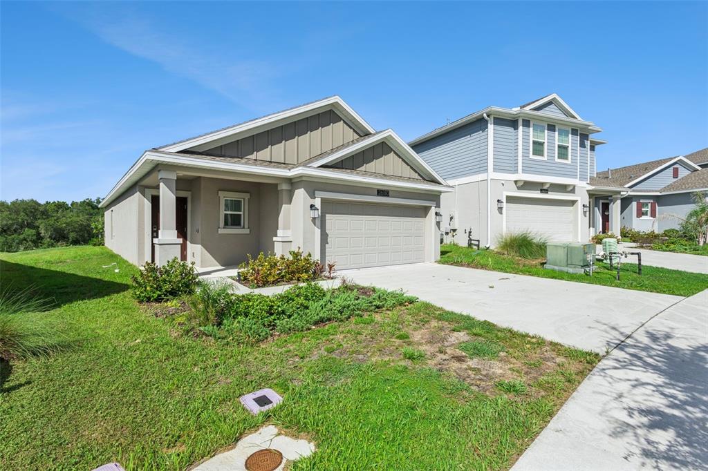 A single-story house with a beige stucco exterior and a two-car garage — 26180 FEATHERGRASS CIRCLE, LEESBURG, FL