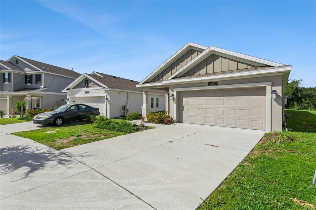 A single-story suburban house with a beige garage and tan siding under a blue sky — 26180 FEATHERGRASS CIRCLE, LEESBURG, FL