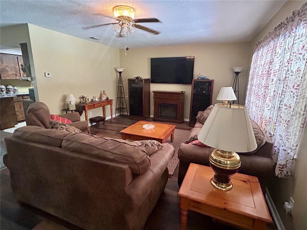 A living room features wood-look flooring, a brown sofa, a recliner, and a ceiling fan — 4047 S GARLAND TERRACE, INVERNESS, FL
