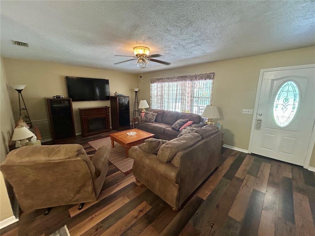A living room features wood-look flooring, a brown sofa, a recliner, and a front door — 4047 S GARLAND TERRACE, INVERNESS, FL