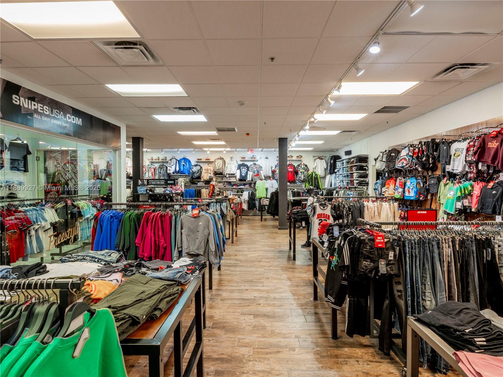 A retail clothing store features rows of apparel racks, wood-look flooring, and recessed ceiling lighting — 1345 Washington Ave, Miami Beach FL 33139, MIAMI BEACH, FL