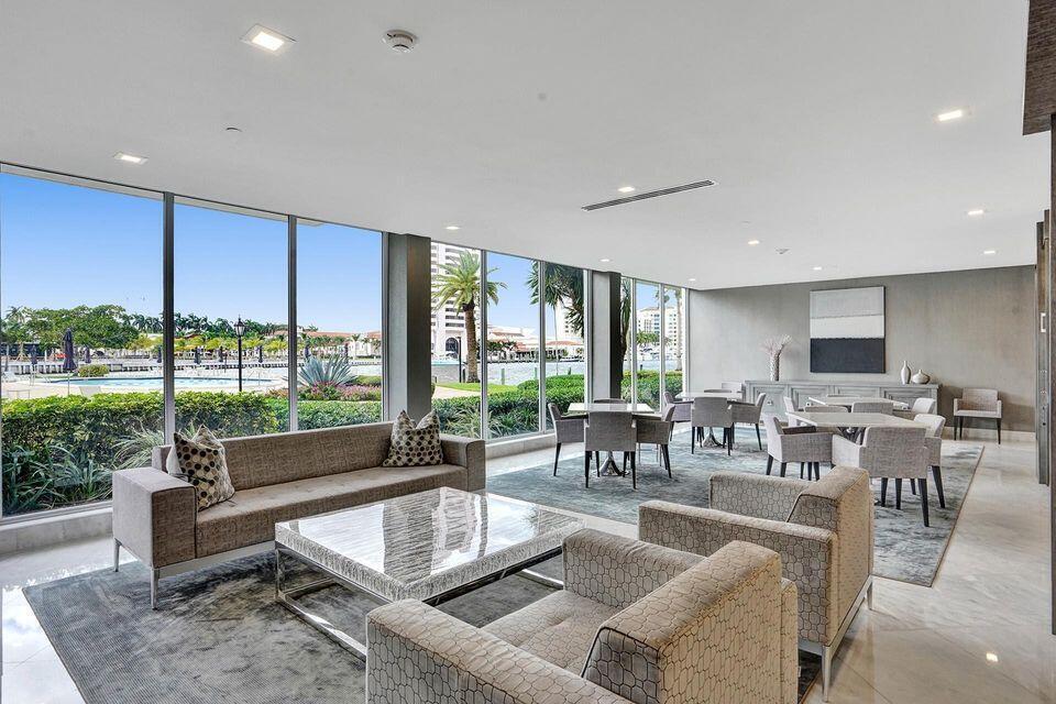 A modern lounge area features floor-to-ceiling windows overlooking a pool and waterfront landscape — 701 E Camino Real # 4b, Boca Raton FL 33432, BOCA RATON, FL