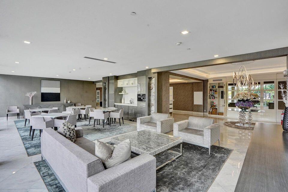 A spacious, modern lounge area features gray upholstered furniture, marble flooring, and a small kitchenette — 701 E Camino Real # 4b, Boca Raton FL 33432, BOCA RATON, FL