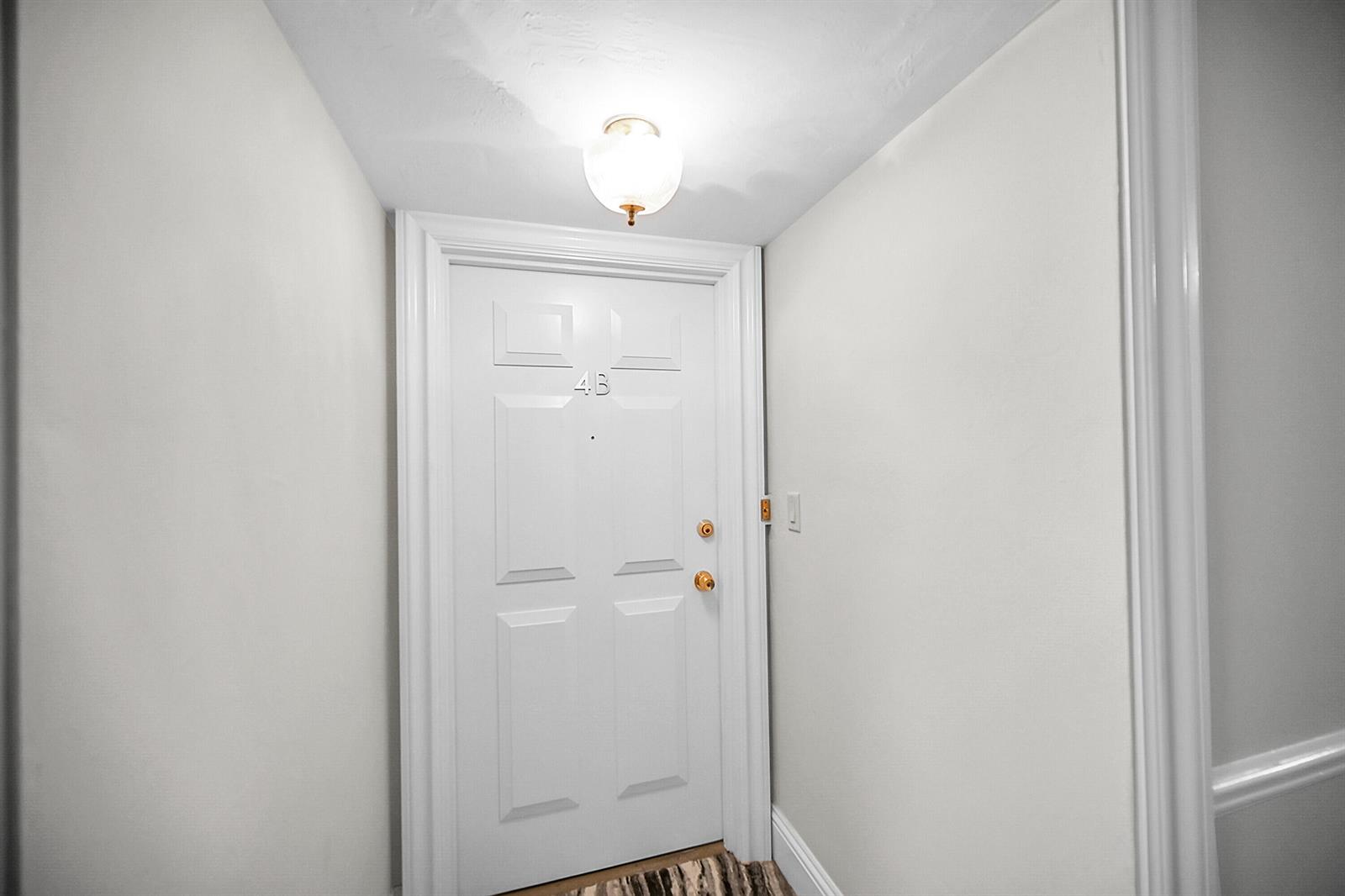 A white interior door labeled 4B is centered in a small, brightly lit hallway — 701 E Camino Real # 4b, Boca Raton FL 33432, BOCA RATON, FL