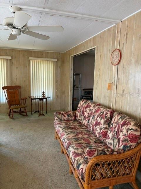 A living room features wood-paneled walls, a floral sofa, a rocking chair, and a ceiling fan — 130 PATRICIA AVENUE UNIT 119, DUNEDIN, FL