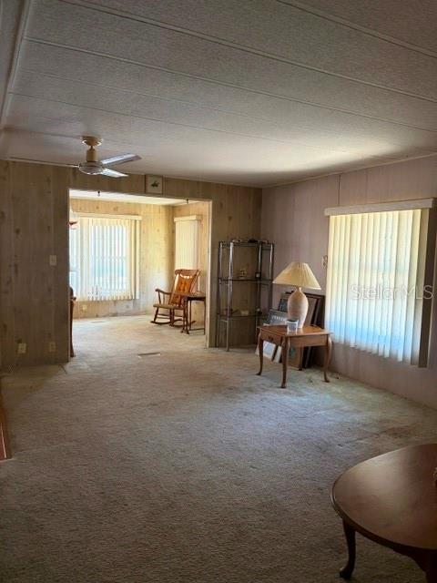 A living room features wood-paneled walls, beige carpeting, a ceiling fan, and a side table — 130 PATRICIA AVENUE UNIT 119, DUNEDIN, FL