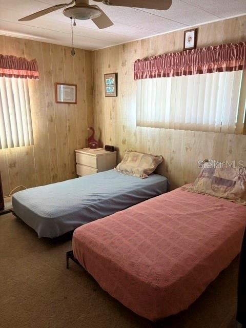 A bedroom features two twin beds, wood-paneled walls, and vertical blinds on the windows — 130 PATRICIA AVENUE UNIT 119, DUNEDIN, FL
