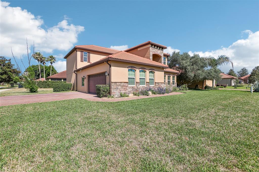 A two-story stucco house with a tile roof, stone accents, and a brick driveway — 10151 YONAOMI CIRCLE, CLERMONT, FL