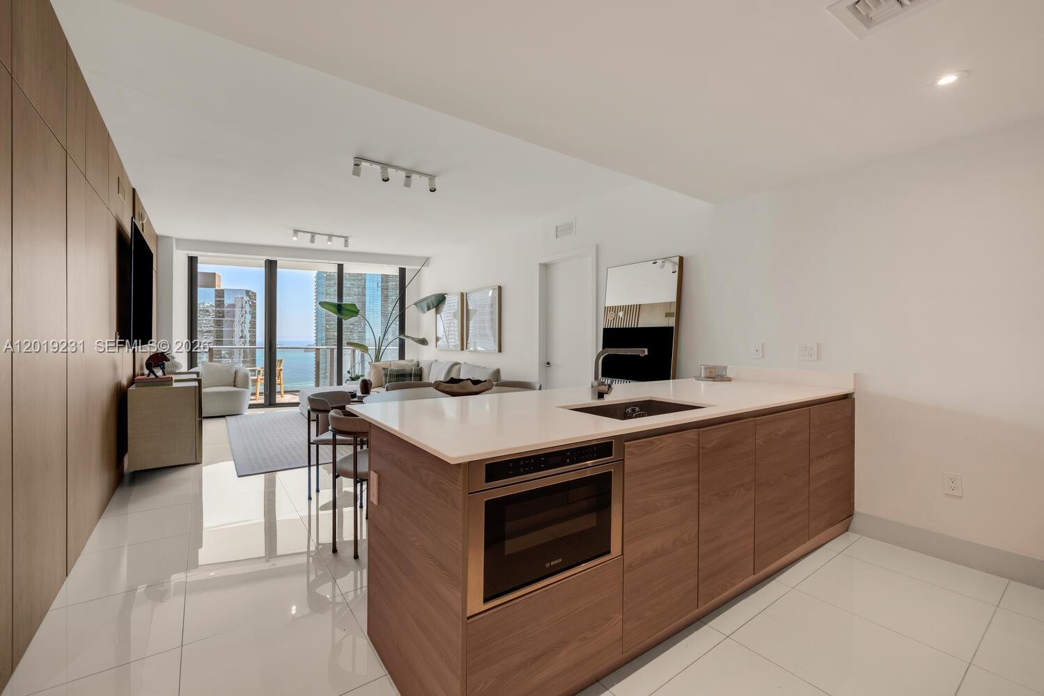 A modern kitchen island with a built-in microwave faces a living area with ocean views — 1300 S Miami Ave # 2602, Miami FL 33130, MIAMI, FL