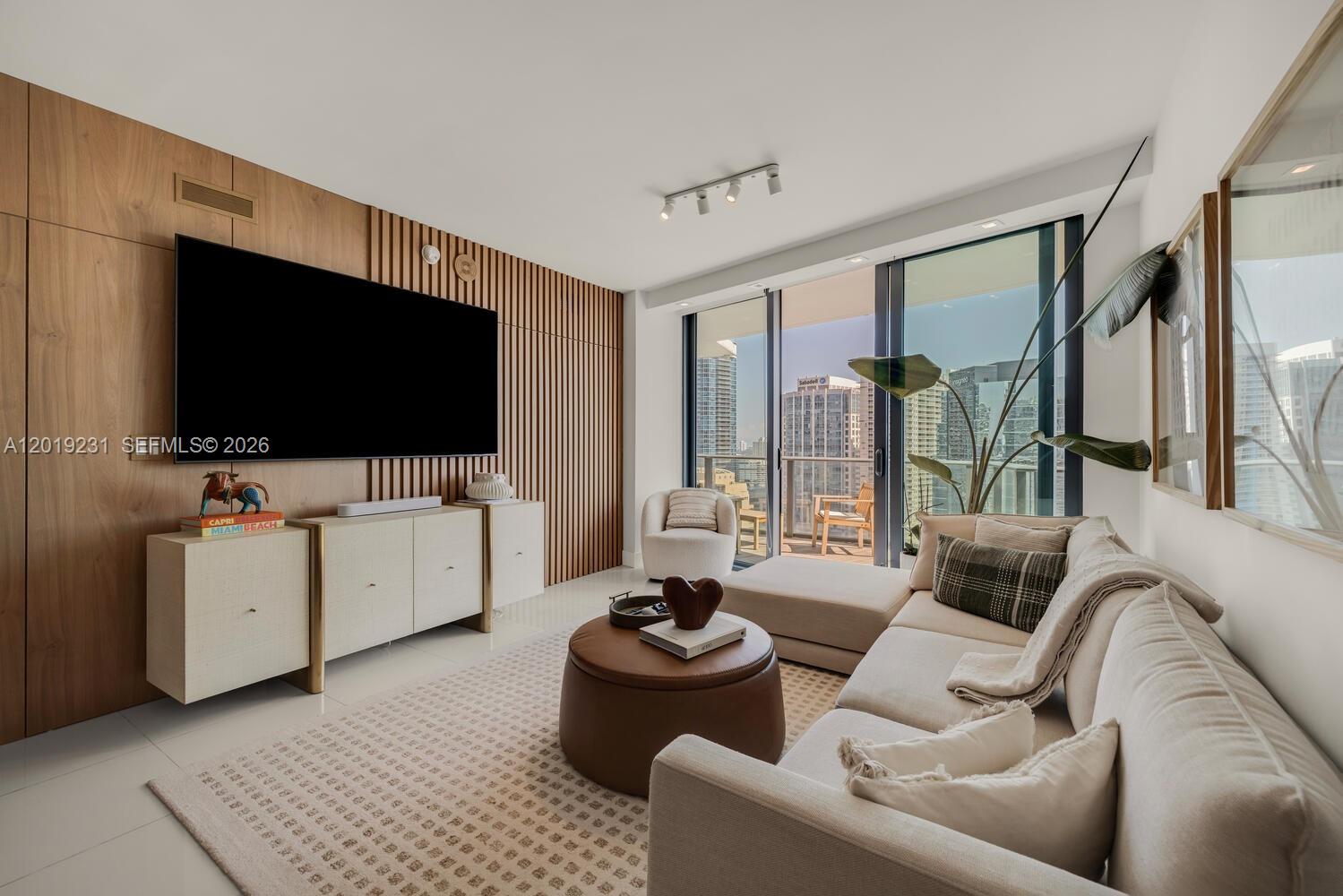 A modern living room features a wood-slat accent wall, a large television, and floor-to-ceiling windows — 1300 S Miami Ave # 2602, Miami FL 33130, MIAMI, FL