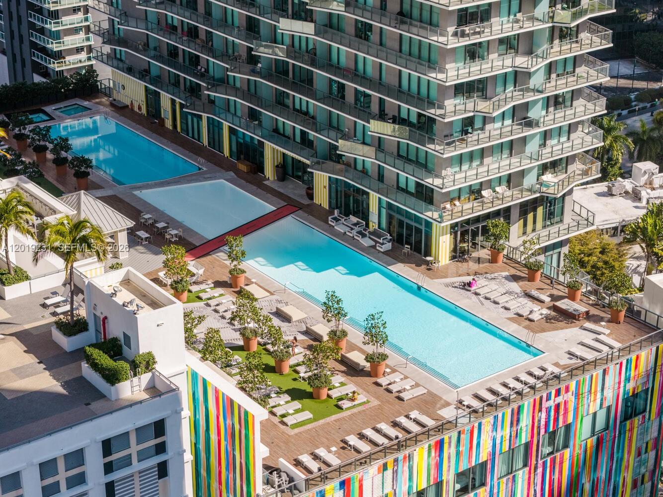 An aerial view shows a high-rise building with multiple swimming pools and lounge areas — 1300 S Miami Ave # 2602, Miami FL 33130, MIAMI, FL