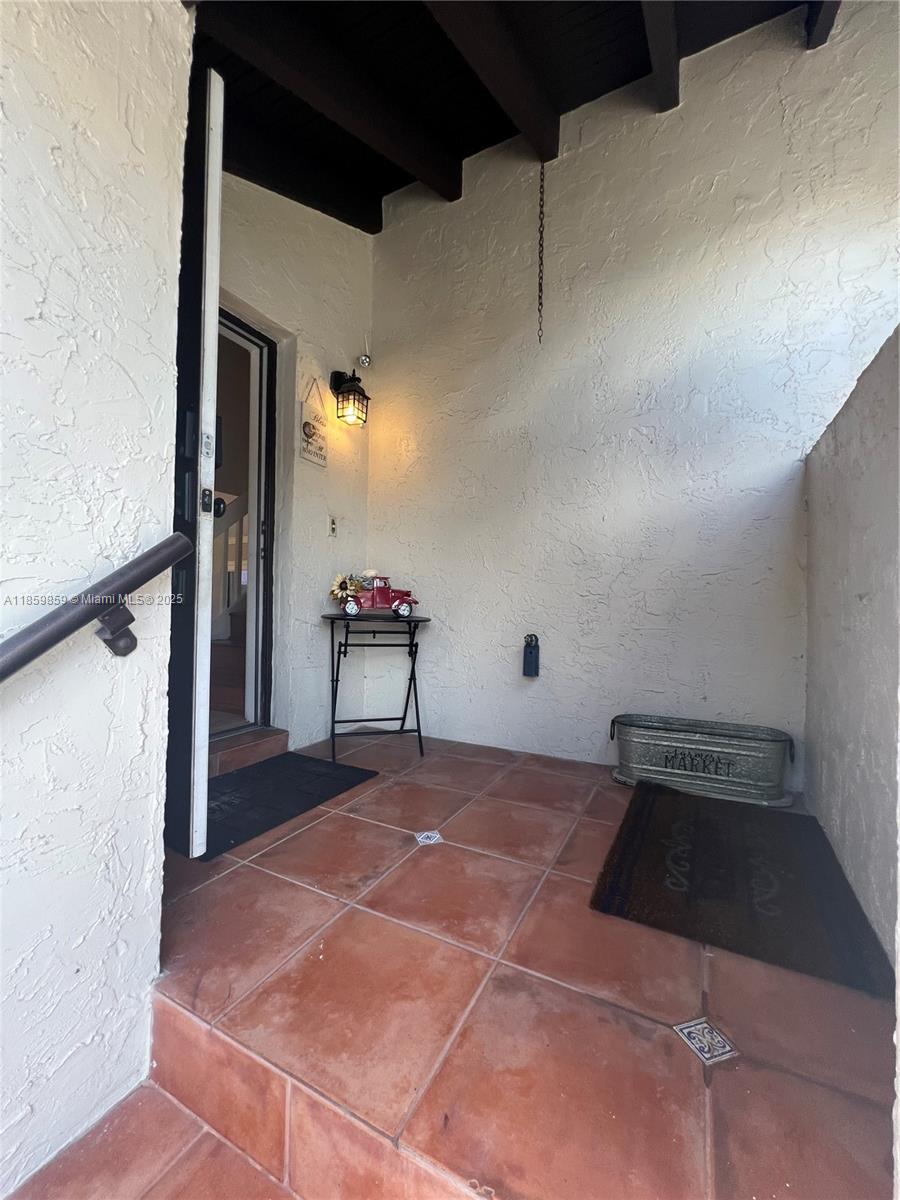 A covered entryway features terracotta tile flooring, a small side table, and a metal planter — 4910 SW 149th Ct # 11B, Miami FL 33185, MIAMI, FL